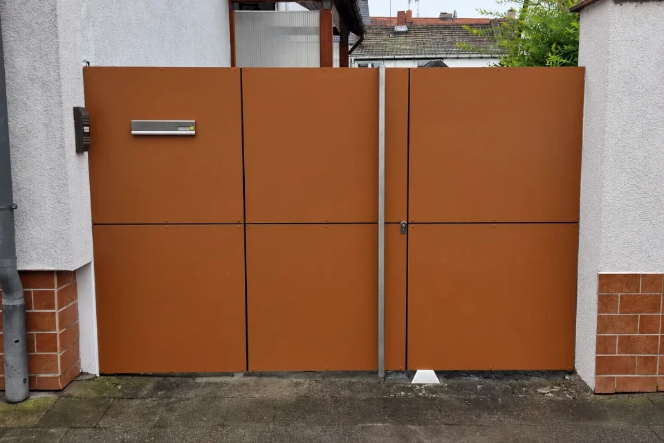 Nachher: neues vollverkleidetes Hoftor in Rostbraun mit Briefkastenschlitz und Edelstahl-Griffstange an derselben Einfahrt